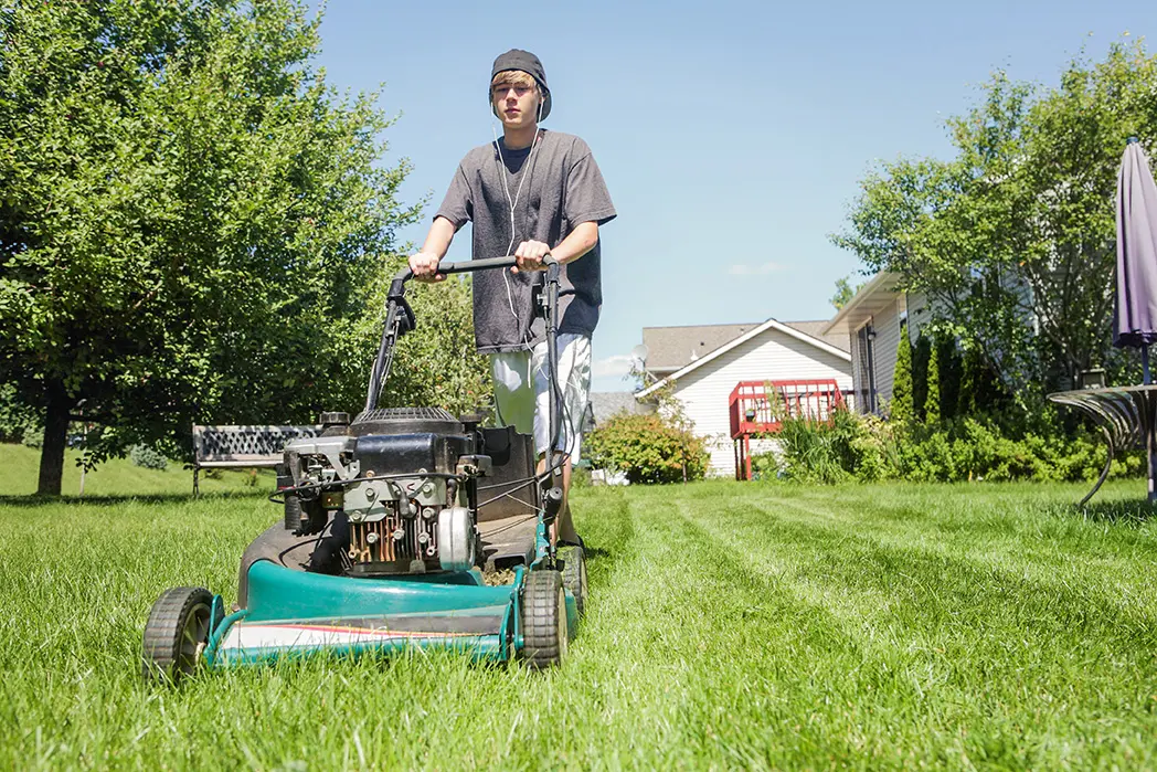 Teenage boy mowing lawn