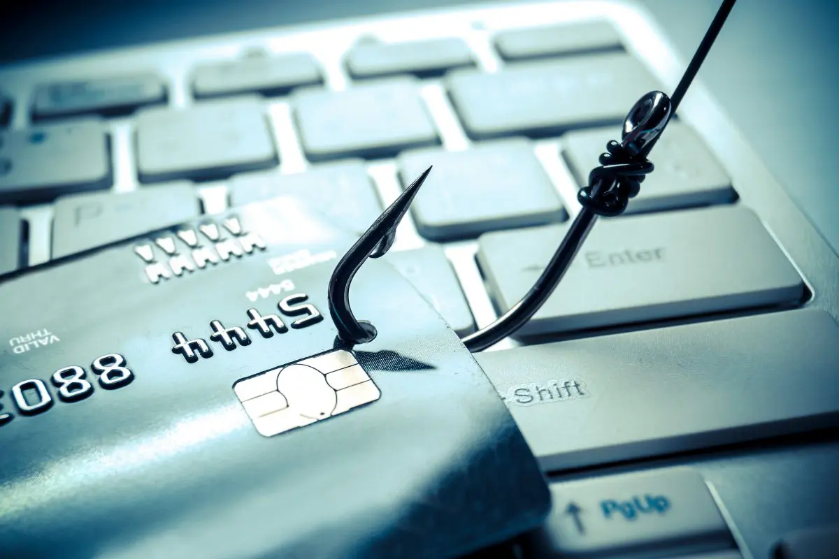 fish hook through credit card on laptop - Symbolizes phishing activity