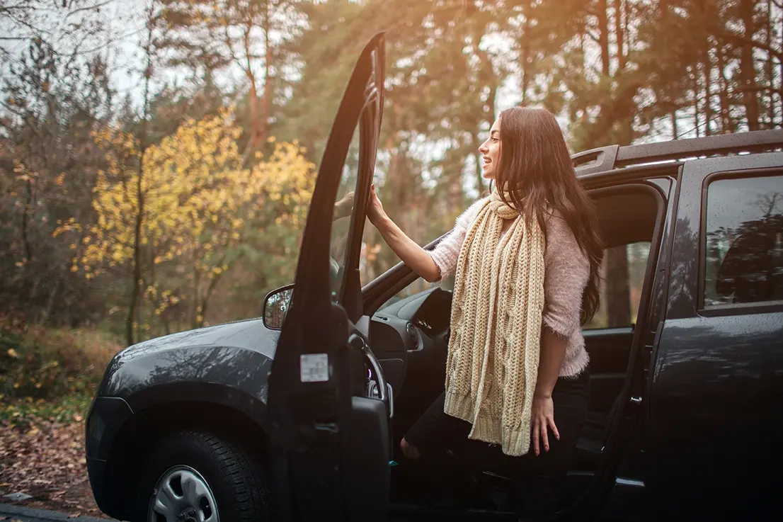 Woman getting out of SUV to check out Fall Foliage
