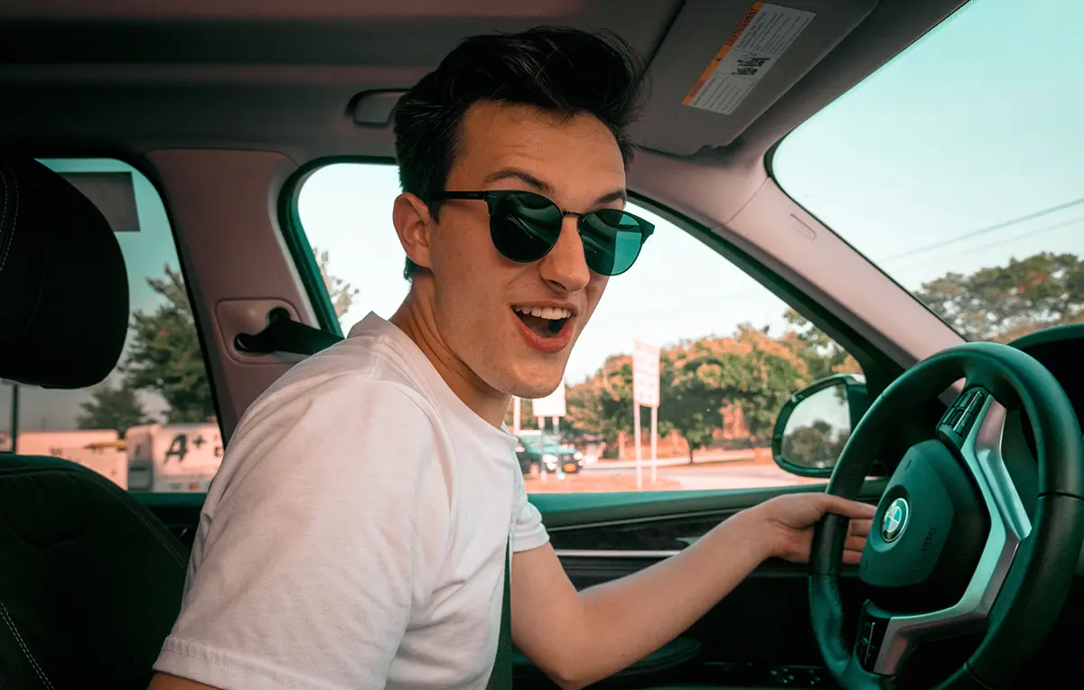Happy teen boy driving car