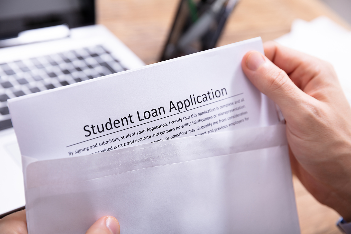 Close-up Of A Person's Hand Removing Student Loan Application Form From White Envelope;
