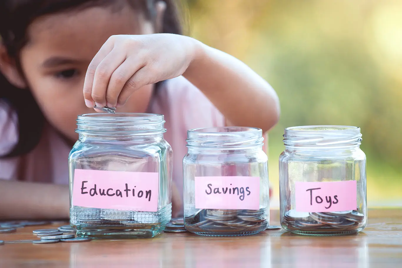 Little Girl putting money in savings jars