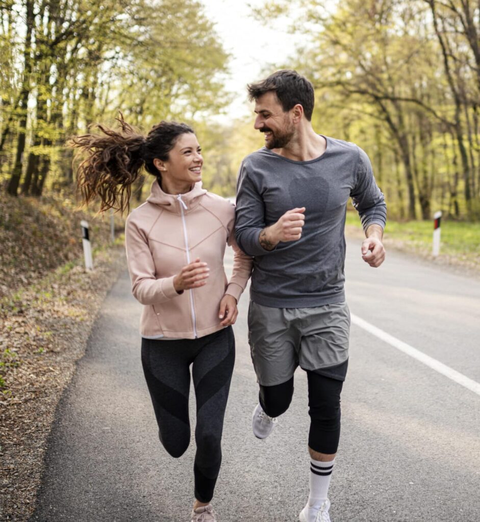 Happy athletic couple having fun while running in spring day