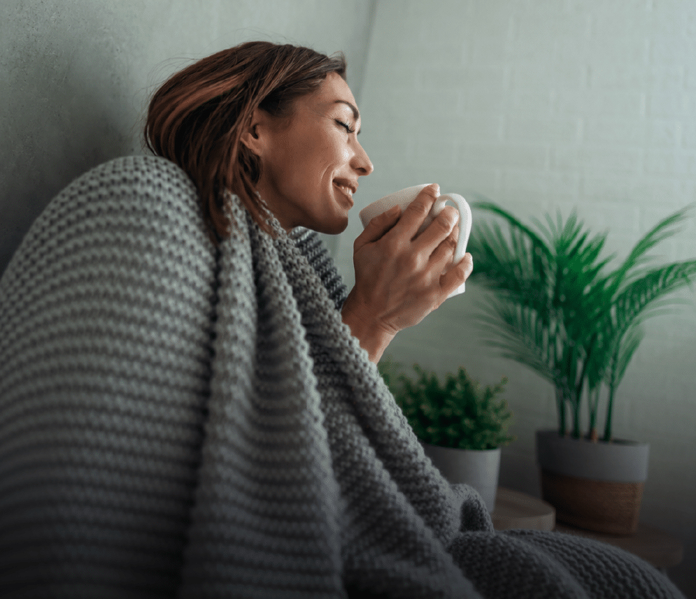 woman drinking coffee wrapped in blanket